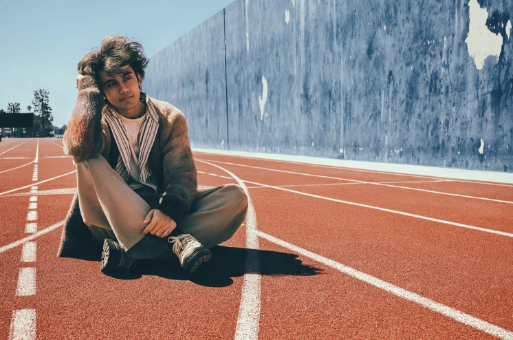 aron! seated on a red running track in an official publicity photograph