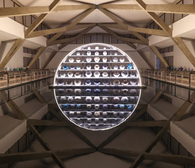 Illuminated circular display of crafted vessels reflected in a dark pool at Homo Faber 2026