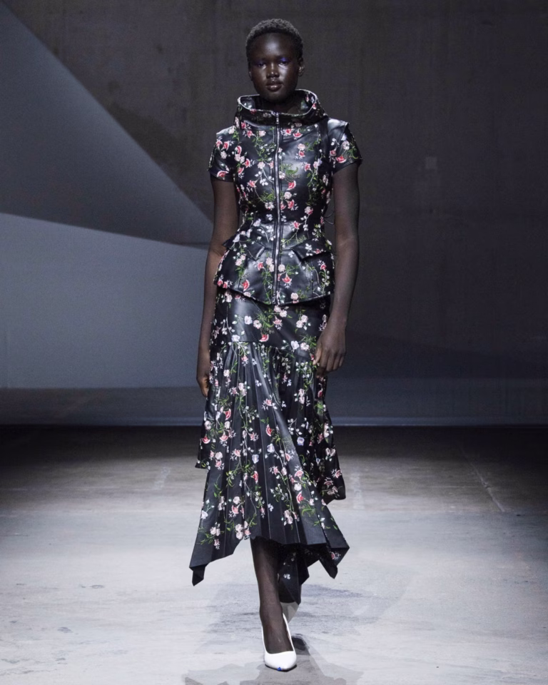 Model wearing Petra Fagerström’s floral high-necked top and asymmetric pleated skirt on the Spring/Summer 2027 runway.
