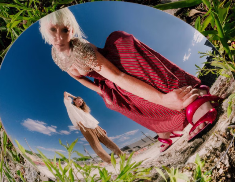 Sylvan Esso’s Amelia Meath and Nick Sanborn reflected in an outdoor mirror in their Ow ∞ press photograph.