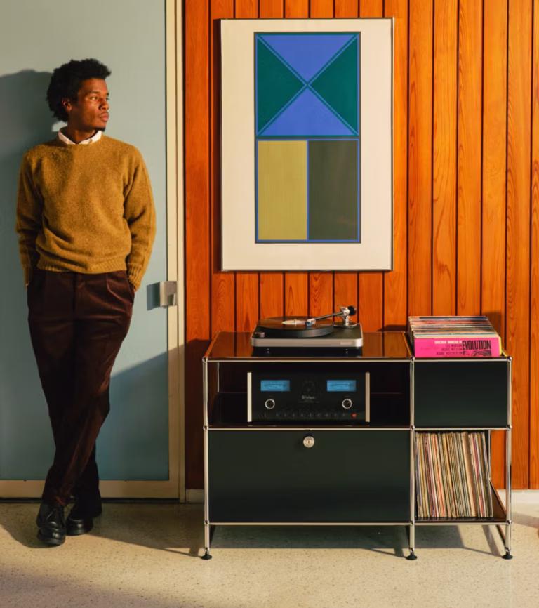 USM and Symbol Audio record stand with a turntable, amplifier and vinyl in a wood-panelled listening space.