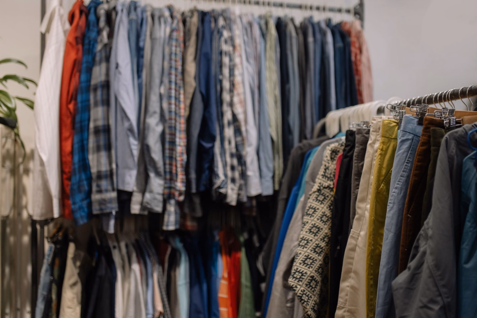 Secondhand shirts and trousers on clothing racks, showing varied colors, patterns and fabrics; no people are pictured.