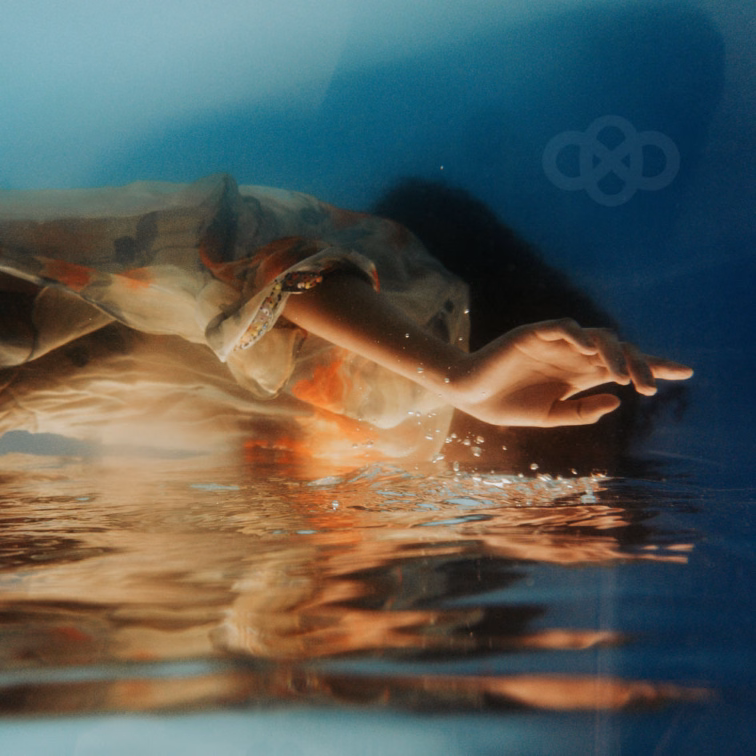 Under the Surface cover artwork showing an outstretched hand and a partially submerged figure, with warm reflections against deep blue water.